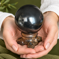Shungite sphere held in a hand for scale