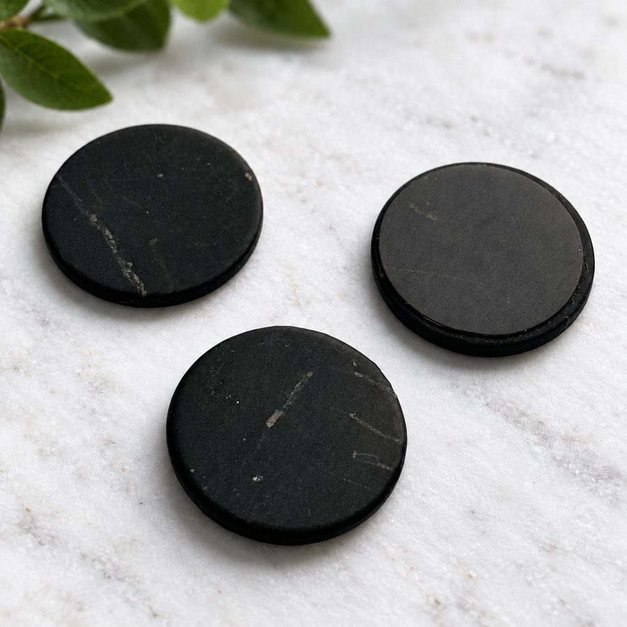 Three 20 mm shungite phone stickers on white marble
