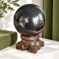 Polished shungite sphere on a wooden stand on a home bookshelf