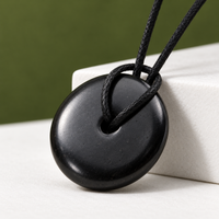 Small shungite torus pendant on a black cord, on white