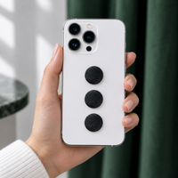 White phone with three shungite stickers on the back, held in hand