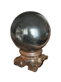 Polished shungite sphere on its wooden stand
