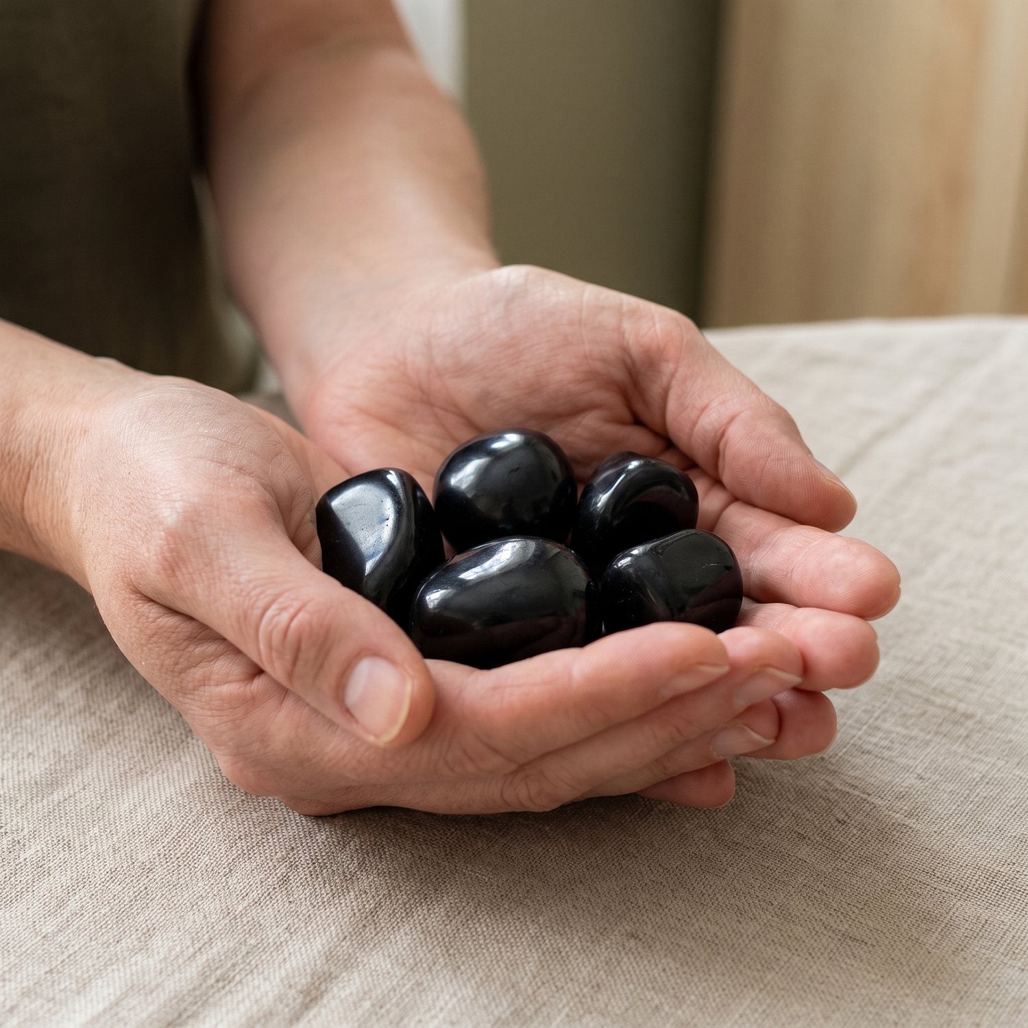 Tumbled shungite stones held in two cupped hands