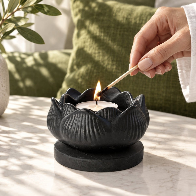 A carved shungite lotus tealight holder being lit with a match
